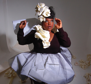 A young black actress in a tutu and white folded hat, posing for the camera